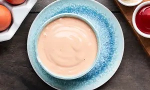 Una ciotola di salsa rosa cremosa, perfetta per la tua prossima ricetta. Accanto, uova e condimenti.
