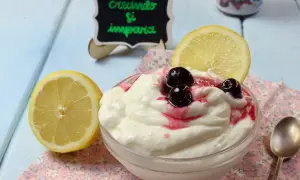 Deliziosa mousse al limone con ciliegie e una fetta di limone, servita in una ciotola su un tovagliolo fiorato.