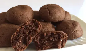 Biscotti al cioccolato morbidi con cuore filante. Alcuni sono interi, altri spezzati per mostrare il ripieno goloso.