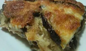 Una fetta di parmigiana di melanzane bianca, dorata e filante, con strati di melanzane e formaggio fuso.