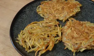 Tre croccanti rosti di patate in padella, dorati e pronti per essere gustati.