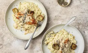 Due piatti di cremoso riso con pollo, guarniti con carciofi e rosmarino. Un piatto invitante e saporito.
