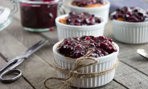 Deliziosa marmellata di amarene ricetta in ciotoline, pronta per essere gustata. Un vasetto pieno e forbici vintage completano la scena.