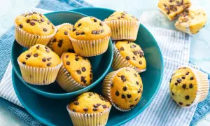 Muffin con gocce di cioccolato dorati e soffici, serviti in una ciotola blu.