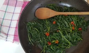 Cicoria in padella, un contorno saporito con peperoncino e un cucchiaio di legno pronto a mescolare.