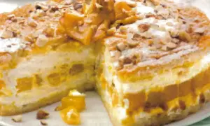 Torta soffice con strati di crema e albicocche, decorata con mandorle e zucchero a velo. Un delizioso tiramisù giallo zafferano.