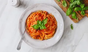 Un piatto invitante di pasta al pomodoro, condita con basilico fresco, pronta per essere gustata.