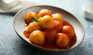Gnocchi di pane in salsa rossa, un piatto rustico e saporito, servito in una ciotola di ceramica grezza.