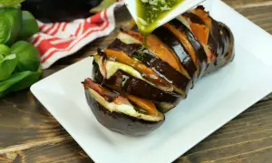 Melanzana ripiena e affettata, condita con un sugo verde. Un'idea gustosa tra i 100 modi per cucinare le melanzane.