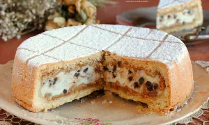Una fetta di cassata al forno, con ripieno cremoso e gocce di cioccolato, cosparsa di zucchero a velo.