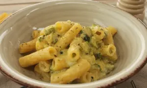 Piatto di rigatoni cremosi con carbonara di zucchine, guarniti con pepe nero macinato fresco.