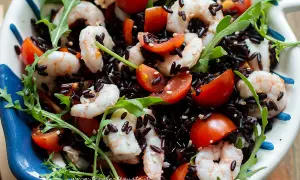 Insalata colorata con riso venere, gamberetti succosi, pomodorini freschi e rucola croccante. Un piatto leggero e gustoso.