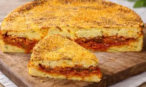 Una fetta di pitta di patate, con strati di ripieno saporito e crosta dorata, pronta per essere gustata.
