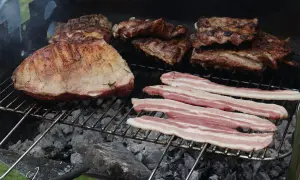 Grigliata di carne con costine, arrosto e pancetta che sfrigolano sulla brace.