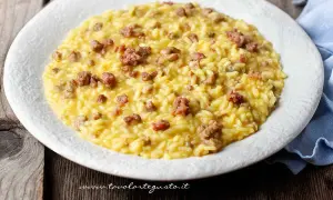 Un cremoso risotto con salsiccia, servito su un piatto bianco, pronto per essere gustato.