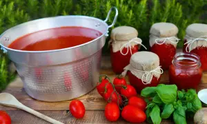 Un grande pentolone di passata di pomodoro, vasetti fatti in casa e pomodori freschi, pronti per la conservazione.