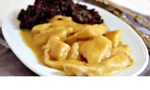 Straccetti di pollo al curry cremosi, serviti con riso nero. Un piatto saporito e invitante.
