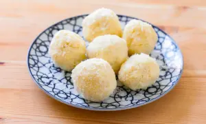 Piatto con dolcetti al cocco, soffici e bianchi, su un fondo di legno.