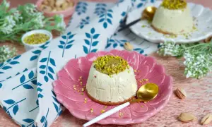 Delizioso semifreddo al pistacchio, guarnito con granella e crema di pistacchi, servito su un piatto rosa.