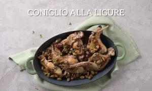 Un saporito coniglio alla ligure, cotto in tegame con olive, pinoli e erbe aromatiche, pronto per essere gustato.