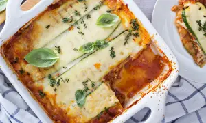 Lasagne di zucchine al forno, dorate e filanti, guarnite con basilico fresco e timo. Un piatto leggero e gustoso.