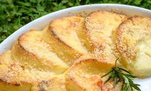 Gnocchi alla romana dorati e gratinati, serviti in una teglia bianca con un rametto di rosmarino.
