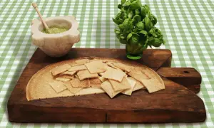 Testaroli al pesto pronti da gustare, con basilico fresco e mortaio.