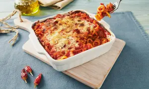 Piatto fumante di pasta alla siciliana, con sugo rosso e formaggio gratinato. Una forchettata pronta per essere gustata.