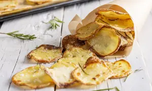 Croccanti chips di patate fatte in casa, condite con sale e rosmarino, servite in un cono di carta.
