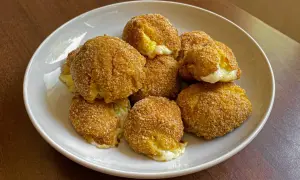 Piatto di polpette di patate dorate e croccanti, con un cuore filante di formaggio.