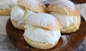 Tre soffici brioche con gelato alla vaniglia, spolverate di zucchero a velo, pronte per essere gustate.
