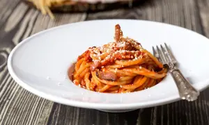 Un piatto di spaghetti alla amatriciana, con guanciale croccante e una salsa rossa saporita. La cipolla, ingrediente chiave della ricetta originale, dona un tocco in più.