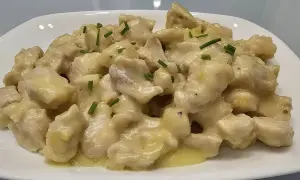 Straccetti di pollo cremosi, un piatto invitante con bocconcini di pollo in una salsa vellutata, guarniti con erba cipollina fresca.