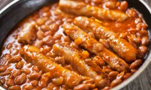 Salsiccia e fagioli in umido, un piatto confortante e saporito, servito in una padella scura.