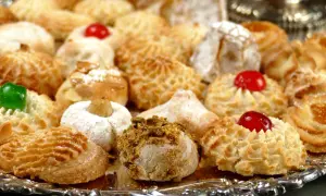 Vassoio pieno di biscotti alle mandorle morbidi, alcuni decorati con ciliegie candite, mandorle e pistacchi.