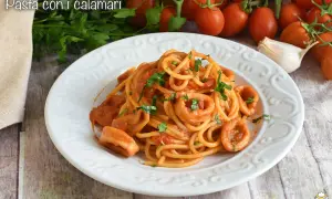 Un piatto di spaghetti con anelli di calamari e pomodoro, guarnito con prezzemolo fresco.