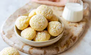 Una ciotola piena di biscotti da inzuppo spolverati di zucchero a velo, pronti per essere gustati con un bicchierino di latte.