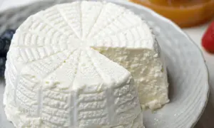 Ricotta fatta in casa, fresca e cremosa, servita su un piatto con mirtilli e fragole.