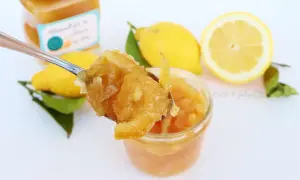 Marmellata di limone ricetta facile: un cucchiaio pieno di delizia, limoni freschi e un vasetto pronto da gustare.