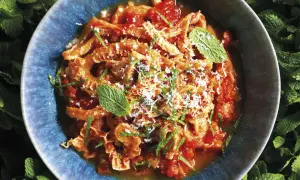 Trippa alla romana in un piatto blu, guarnita con menta e parmigiano. Un classico della cucina romana.