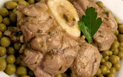 Ossobuco con piselli, un piatto succulento con carne tenera e piselli verdi brillanti, guarnito con una foglia di prezzemolo.