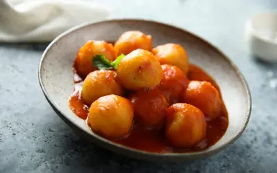Gnocchi di pane in salsa rossa, un piatto rustico e saporito, servito in una ciotola di ceramica grezza.