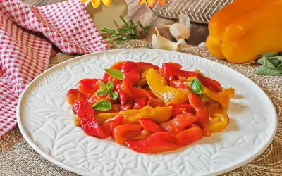 Peperoni rossi e gialli arrostiti in friggitrice ad aria, guarniti con basilico fresco, su un piatto bianco decorato.