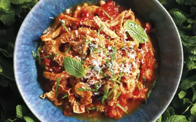 Trippa alla romana in un piatto blu, guarnita con menta e parmigiano. Un classico della cucina romana.