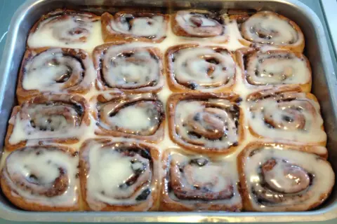 Rotolini alla cannella appena sfornati, ricoperti di glassa bianca e lucida, pronti per essere gustati.