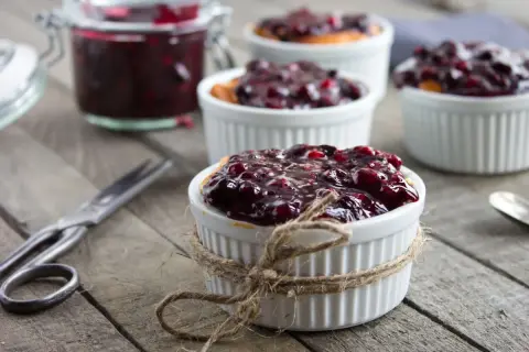 Deliziosa marmellata di amarene ricetta in ciotoline, pronta per essere gustata. Un vasetto pieno e forbici vintage completano la scena.
