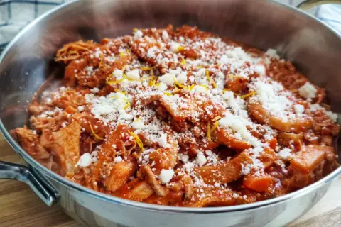 Trippa alla fiorentina fumante in un tegame, cosparsa di parmigiano grattugiato e scorza di limone. Un classico della cucina toscana.