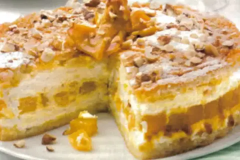 Torta soffice con strati di crema e albicocche, decorata con mandorle e zucchero a velo. Un delizioso tiramisù giallo zafferano.