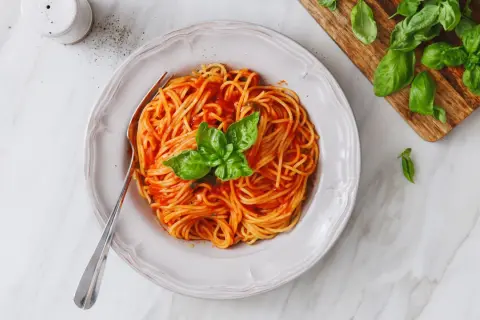 Un piatto invitante di pasta al pomodoro, condita con basilico fresco, pronta per essere gustata.
