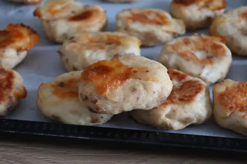 Polpette di pollo dorate e gustose, appena sfornate, con formaggio fuso e pezzetti di carne visibili.